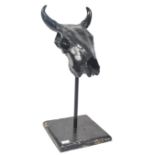 A 20th century plaster cast and resin coated cows / ox skull being ebonised and raised on pole