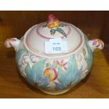 A Clarice Cliff biscuit barrel with raised decoration of fruit, berries and leaves, on a pink