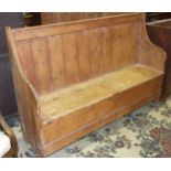An antique pine settle with double-hinged seat, 155cm wide, 102cm high.