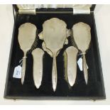 A cased five-piece sterling silver dressing table set with engine turned and floral decoration.