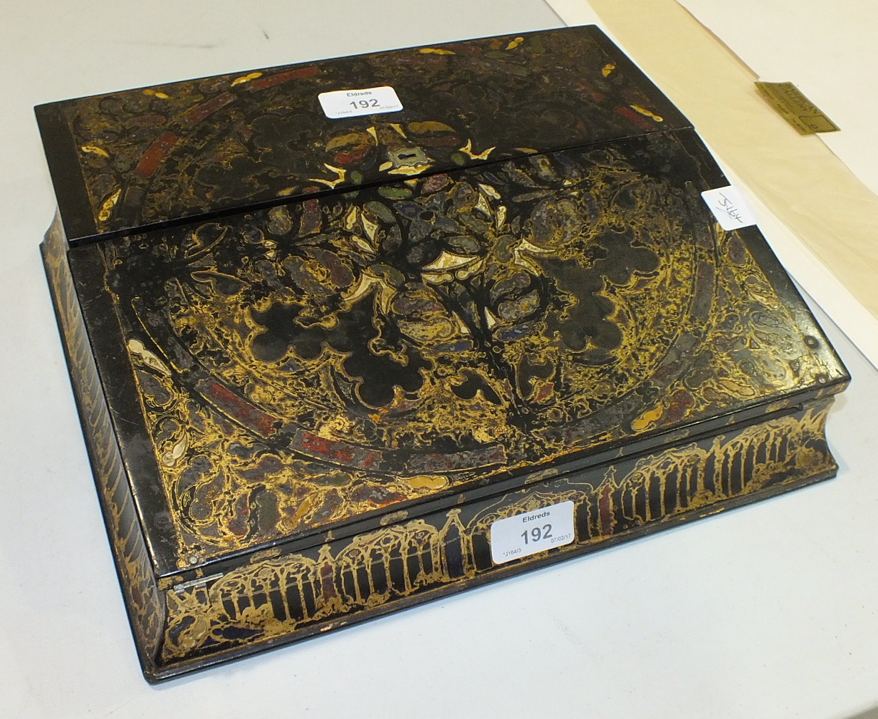 An ebonised lacquered writing slope with hinged top revealing letter rack, inkstand and pen tray and