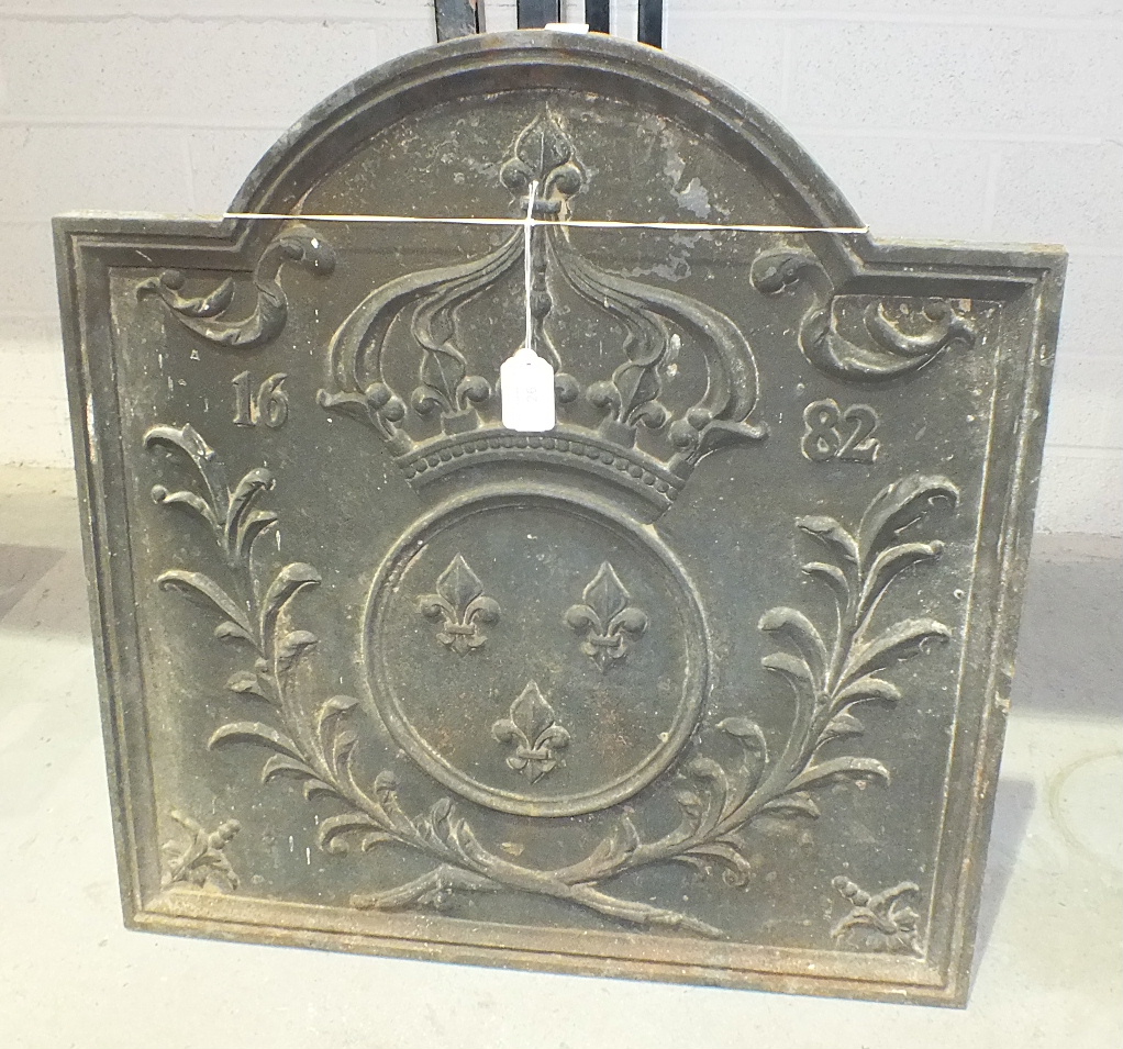 A reproduction cast iron fire back decorated with a crown above three fleur de lys within a circle