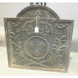 A reproduction cast iron fire back decorated with a crown above three fleur de lys within a circle