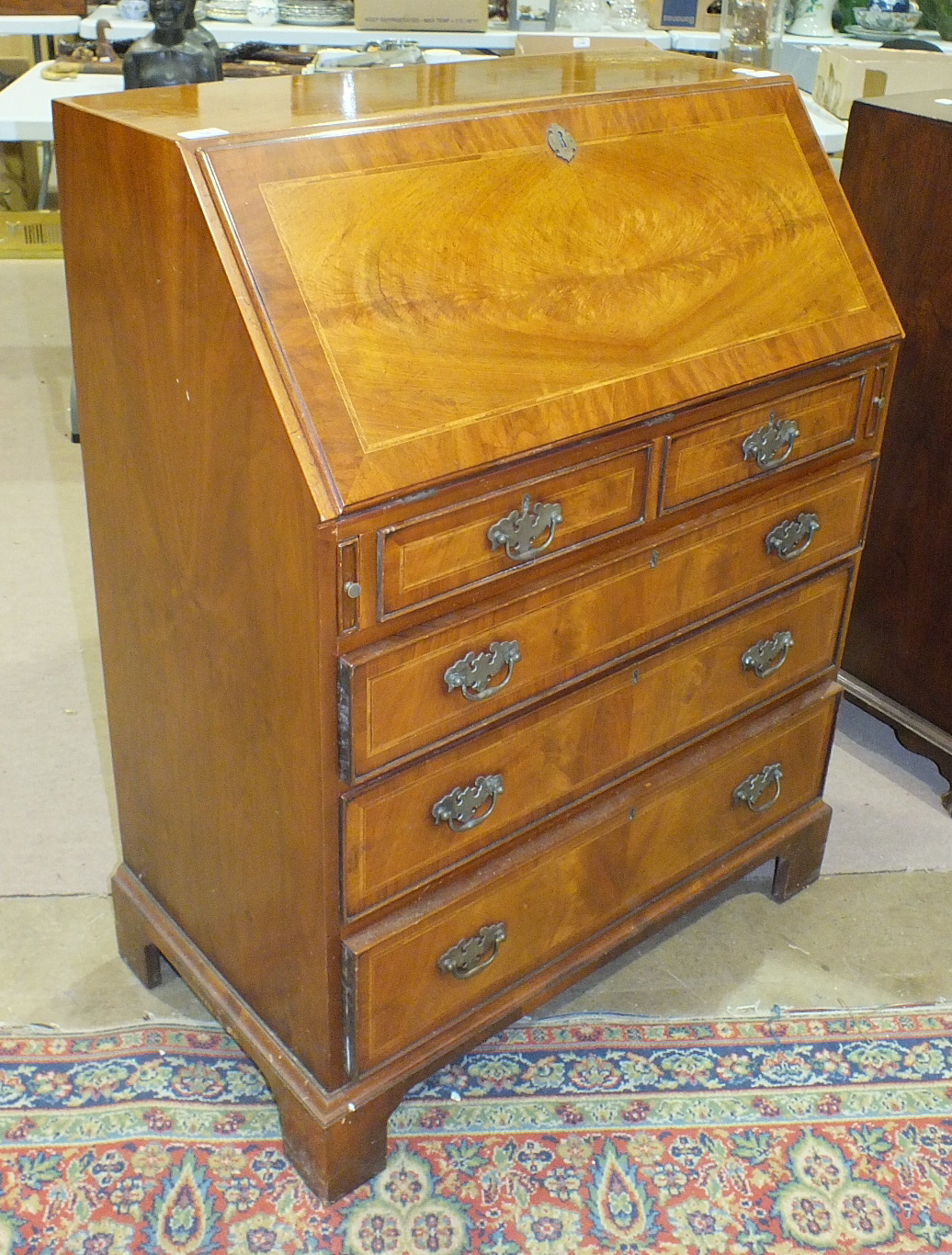 A reproduction walnut bureau, the fall front above two small and three long drawers, on bracket