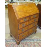 A reproduction walnut bureau, the fall front above two small and three long drawers, on bracket