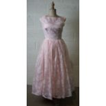 A 1950's pink organza dress with white flock flowers, sleeveless with a full skirt, size 10/12.