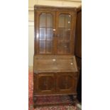 A 1950's oak bureau/bookcase, the top fitted with a pair of glazed doors, the fall-front with