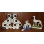 A Staffordshire standing hound with a hare in it's mouth, on oval base, 19.5cm high, a pair of