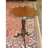 A mahogany and stained wood wine table the shaped circular top on turned column and tripod