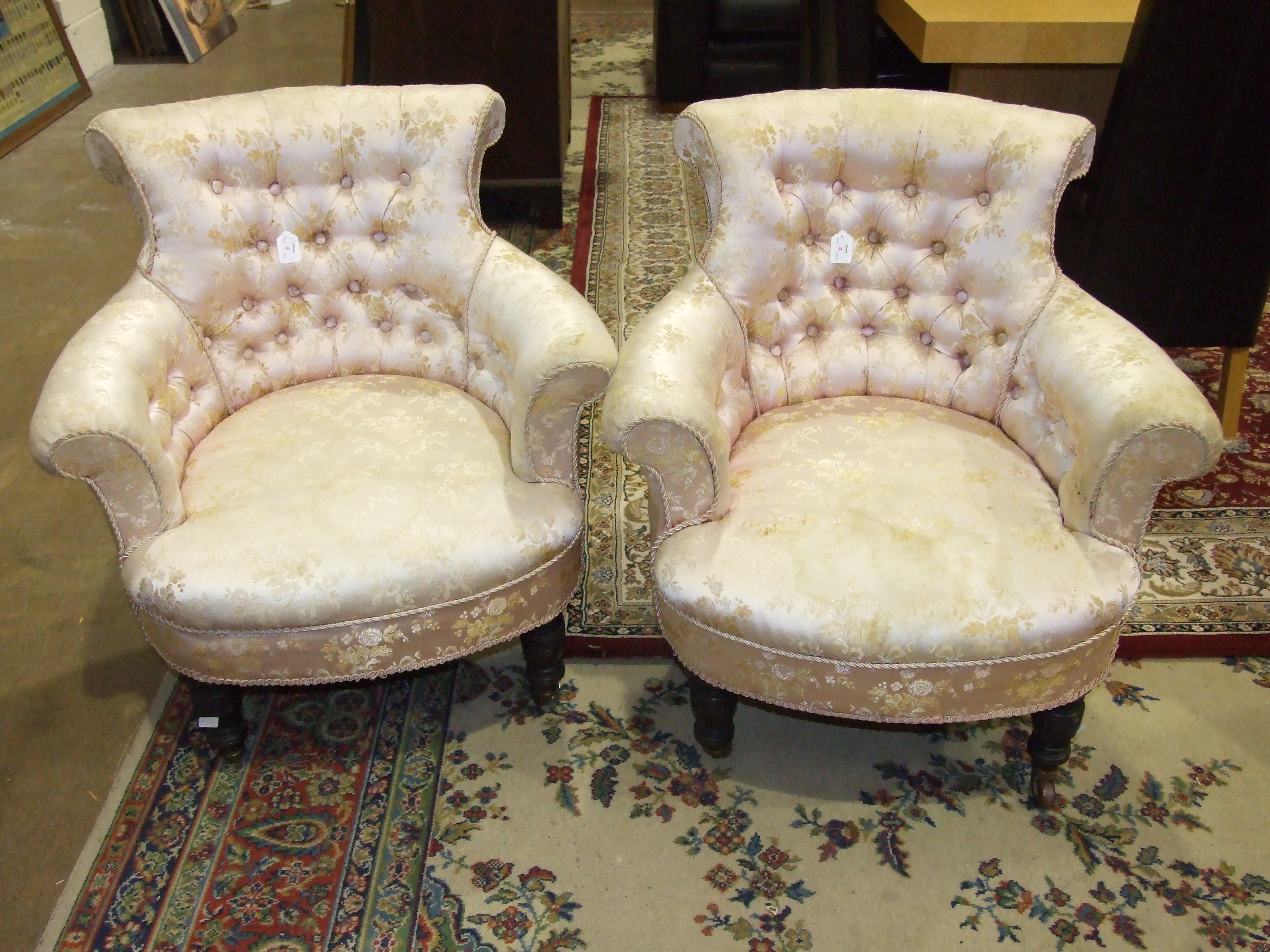 A pair of Late-Victorian button-back tub armchairs on short turned legs with castors.
