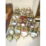 A collection of sixteen ceramic and glass cruets on metal stands, (16).