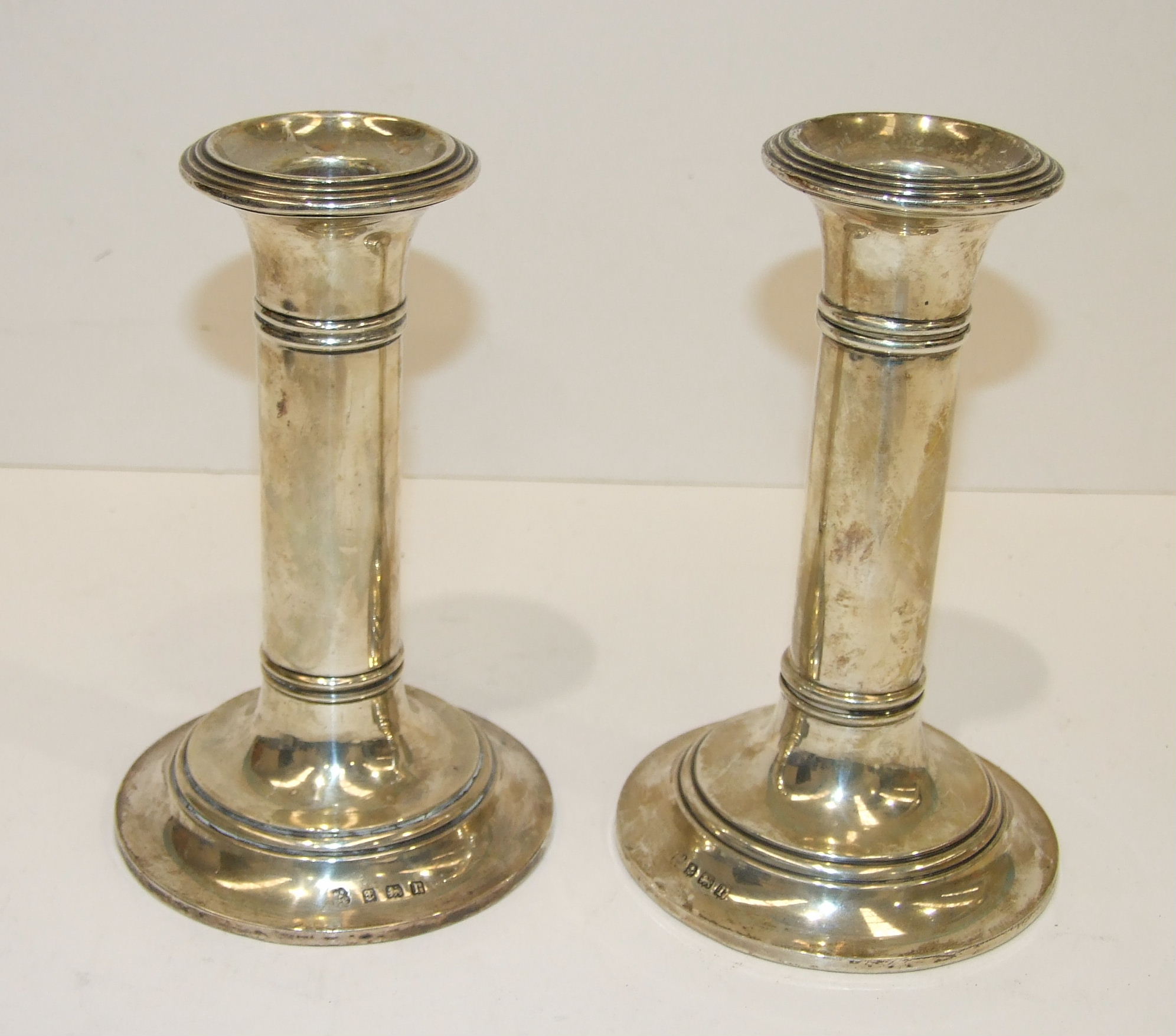 A pair of short silver candlesticks with ring-turned decoration, on circular loaded bases,