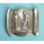 A white metal novelty belt clip cast as two cricketing figures, a bowler and a batsman before a