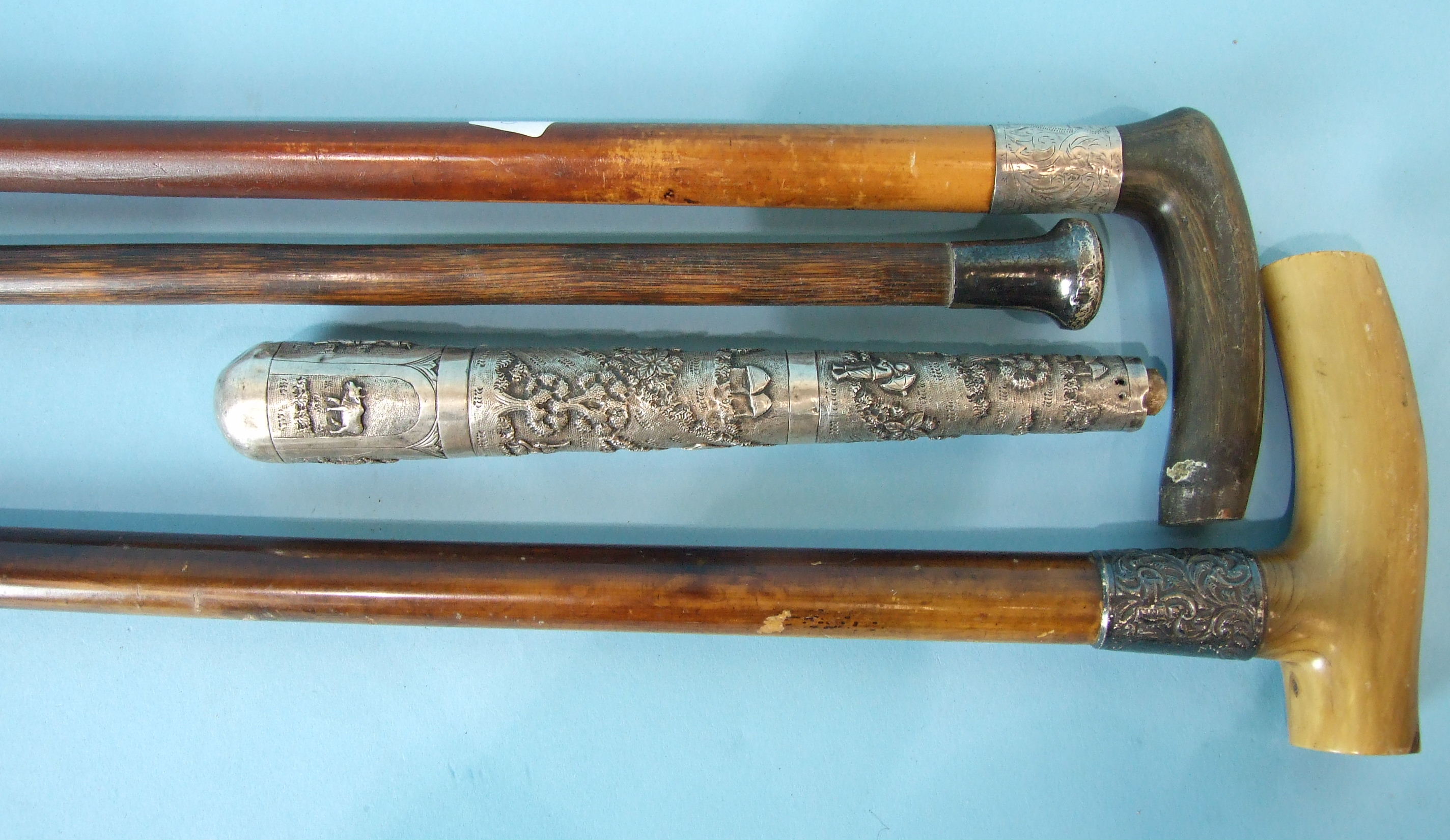 Three silver-mounted walking canes and a Burmese white metal parasol handle, (4).