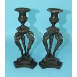 A pair of bronze candle holders supported on three griffins and triform base, 24cm high.