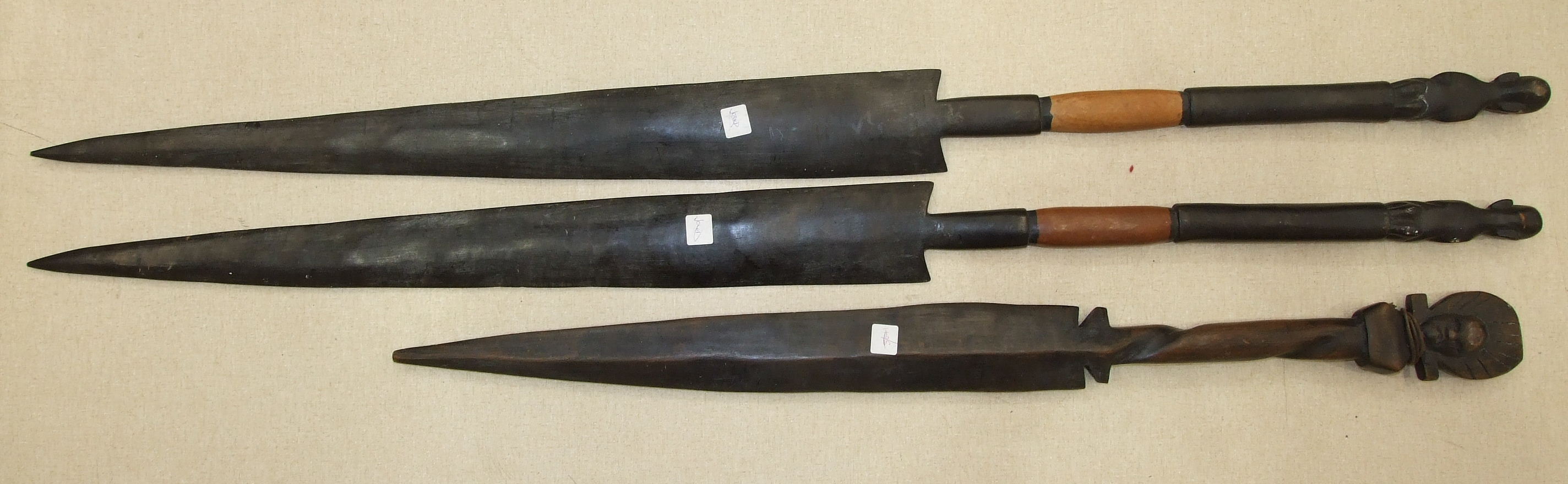 A pair of hardwood ceremonial spears, each with broad tapered blade and figure terminal, 126cm