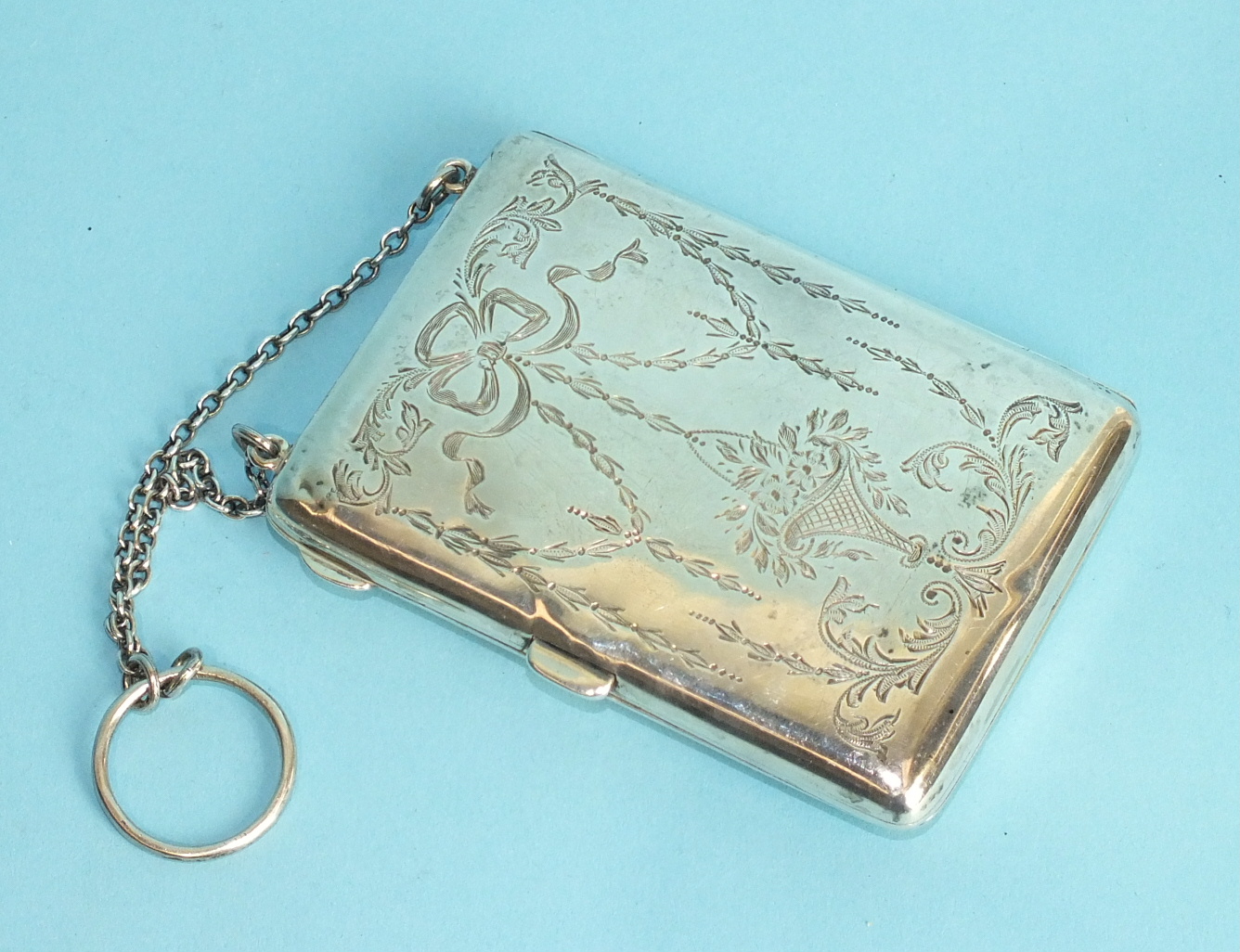 A rectangular purse engraved with ribbon-tied vases and foliage, opening to reveal a leather