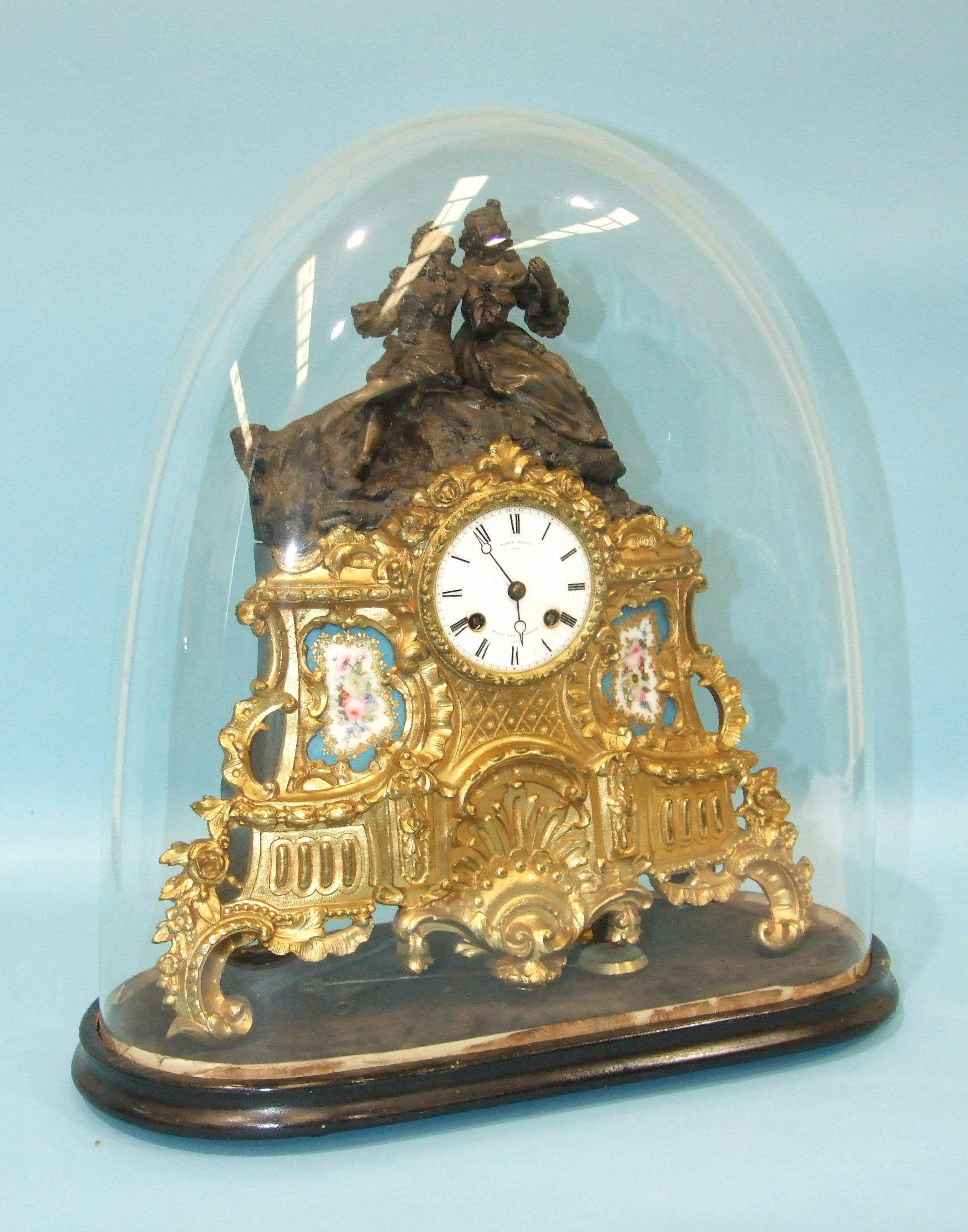 A 19th century French spelter mantel clock, the part-bronzed part-gilt figural case with two