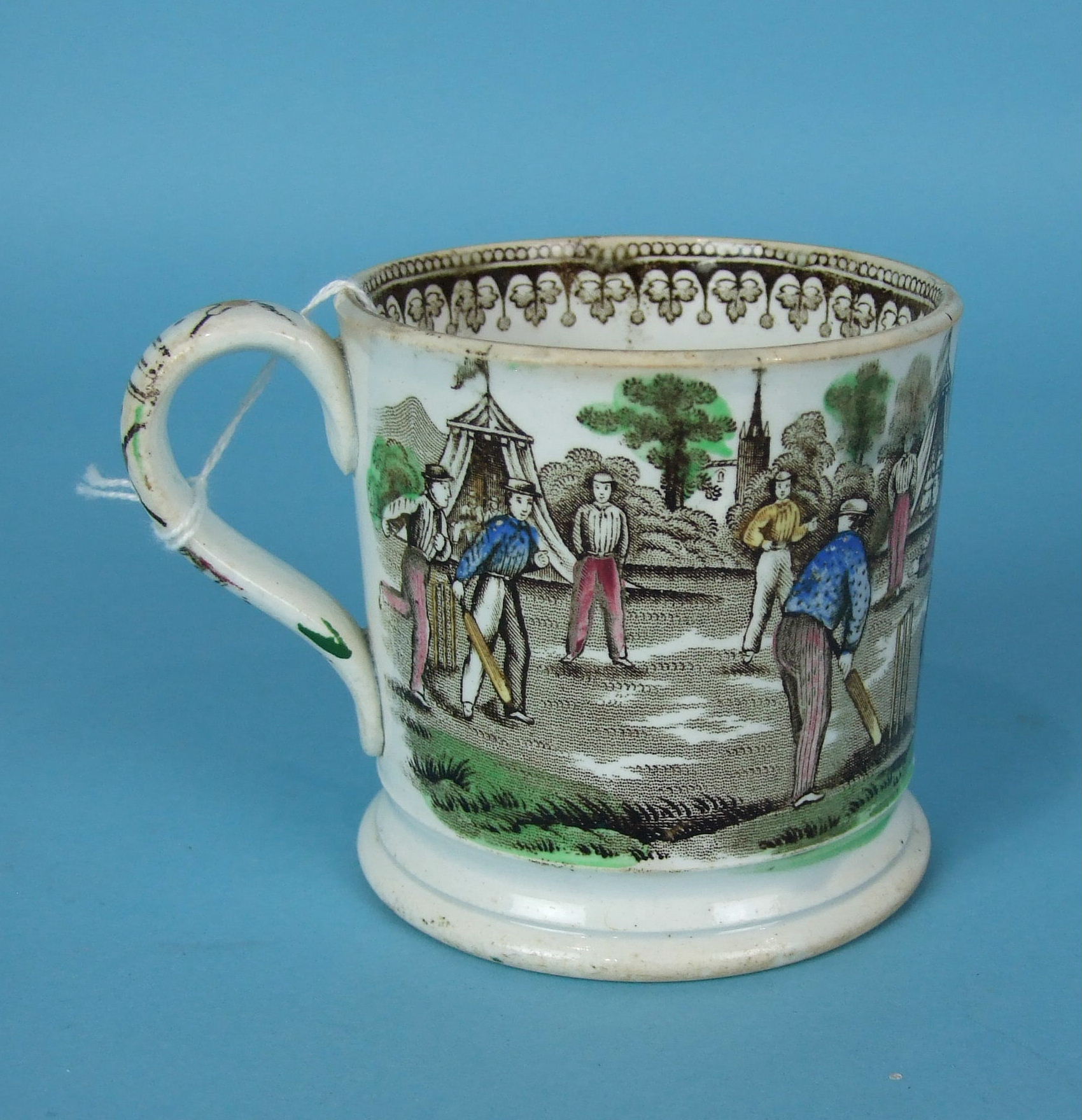 A late-19th century Staffordshire mug, transfer-printed and coloured with a cricketing scene, the