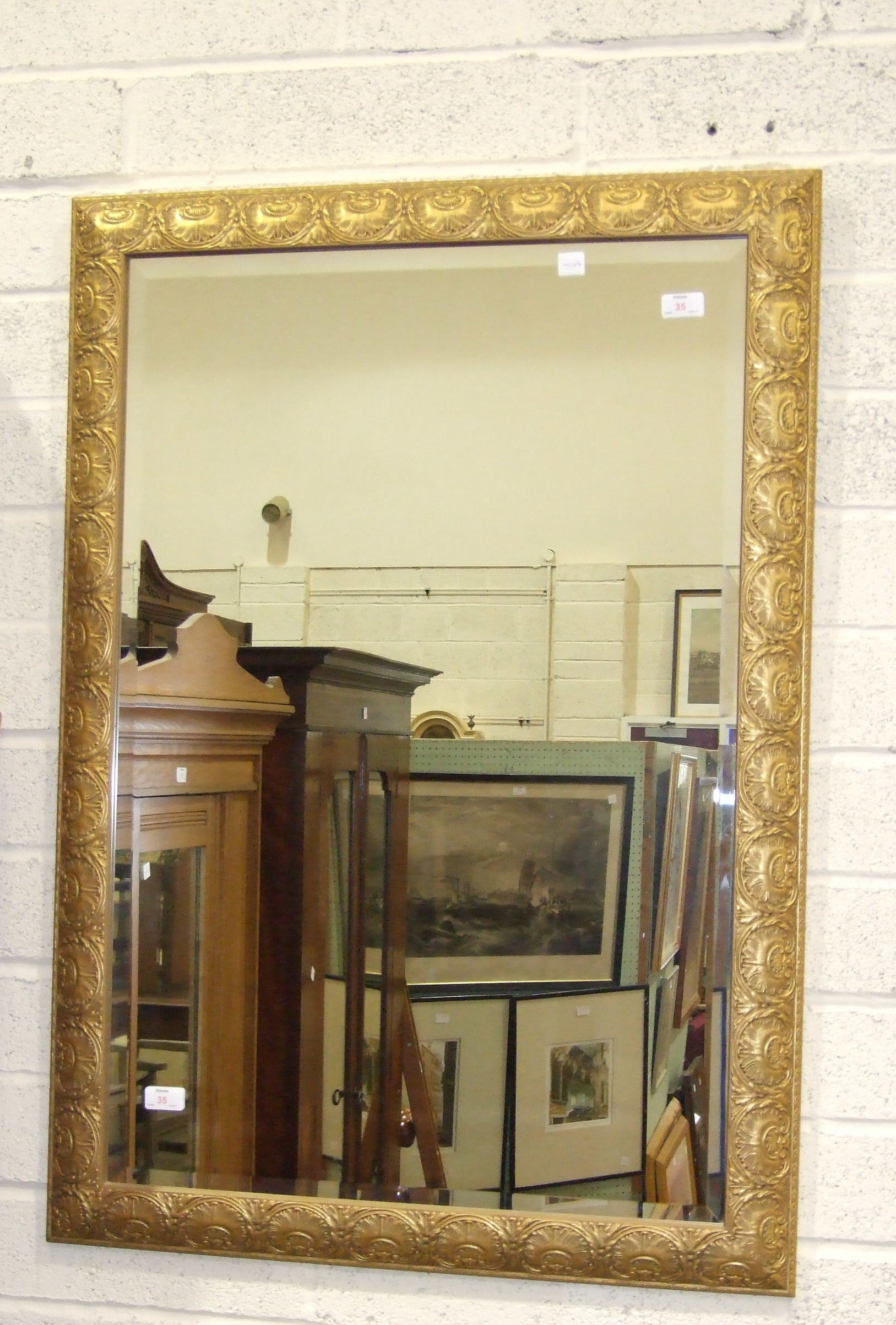 A modern gilt-framed bevelled wall mirror, 105 x 73cm.