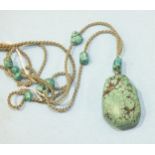 A Chinese turquoise matrix pendant suspended on a silk cord interspersed with turquoise matrix