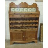 A pine low dresser, the tiled back and shelf above two drawers, three bottle racks and a pair of