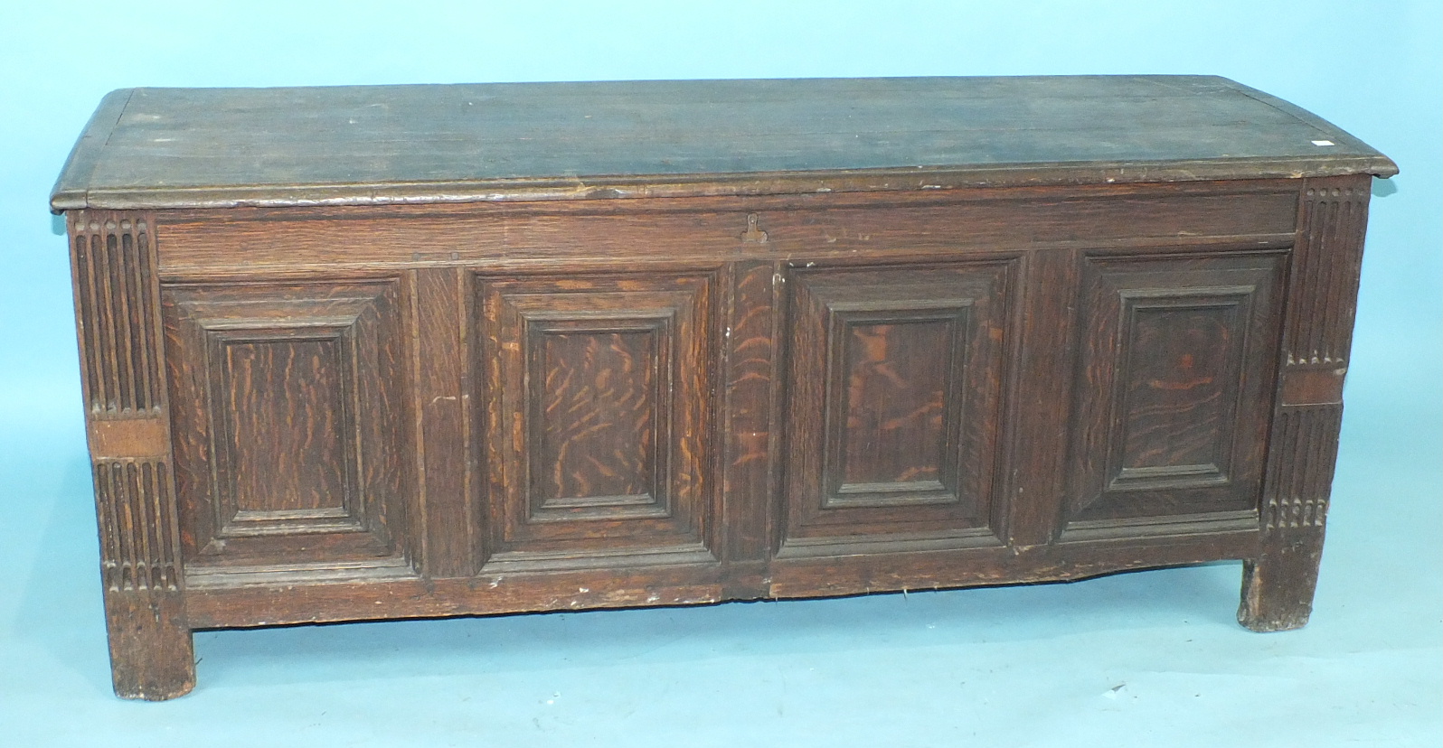 A large antique oak panelled coffer, the fielded panels within reeded stiles extended to form