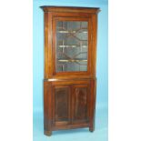 A Georgian mahogany corner cupboard, the moulded cornice above an astragal-glazed door and a pair of