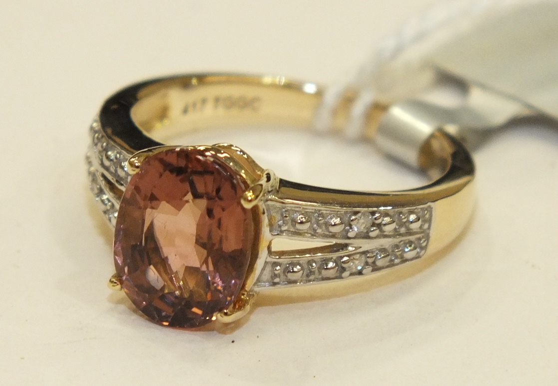 A 9k gold ring set a pink tourmaline between diamond set shoulders, size J, 3g, with certificate