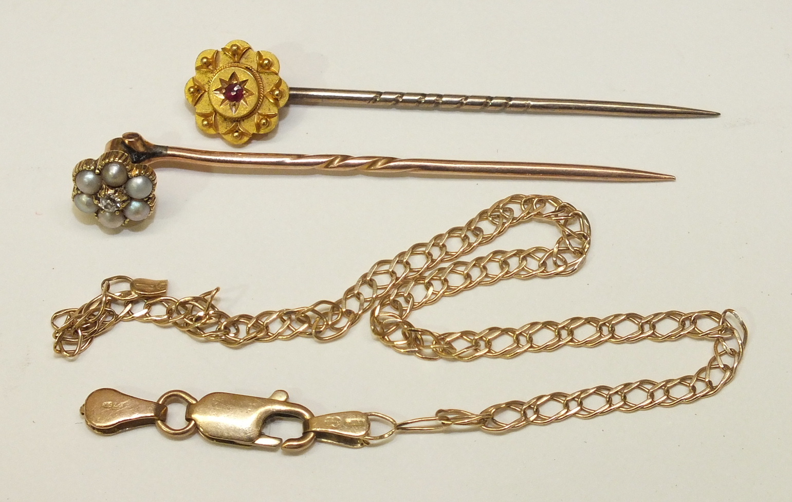 A gold stick pin set diamond and pearl cluster, another stick pin set ruby, 3.3g and a 14k gold