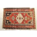 A mid-20th century wool rug, red field with central hexagonal medallions, figures leading camels and