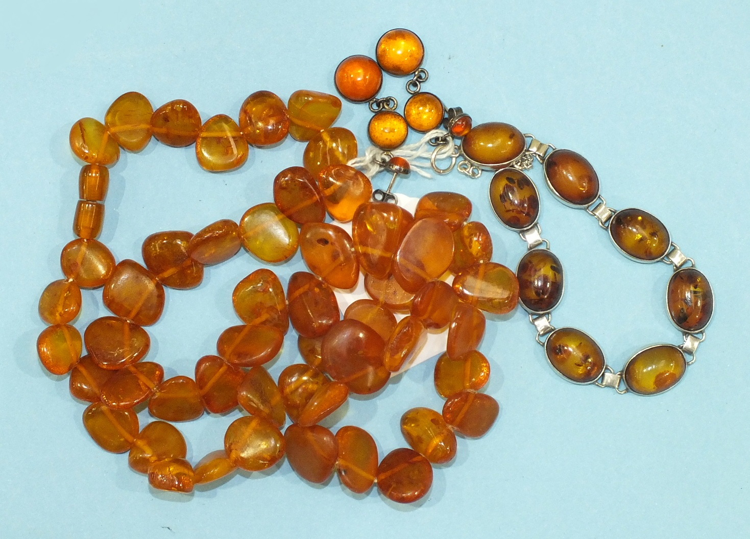 A string of honey-coloured amber flattened beads, 45g, a silver mounted amber bracelet and a pair of