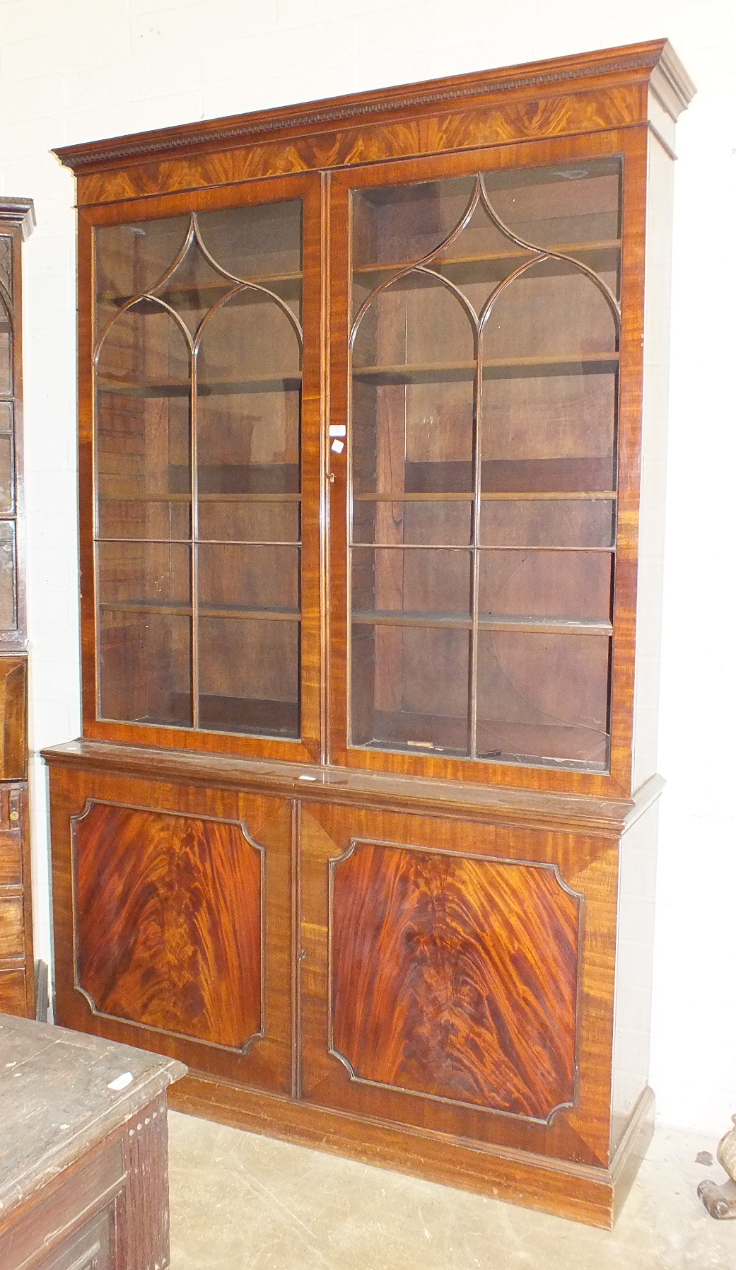 A reproduction mahogany Georgian bookcase, the dentil cornice above a pair of astragal-glazed