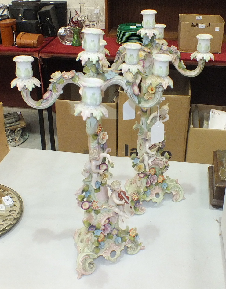 A pair of late-19th century Continental porcelain four-branch candelabra formed as cherub