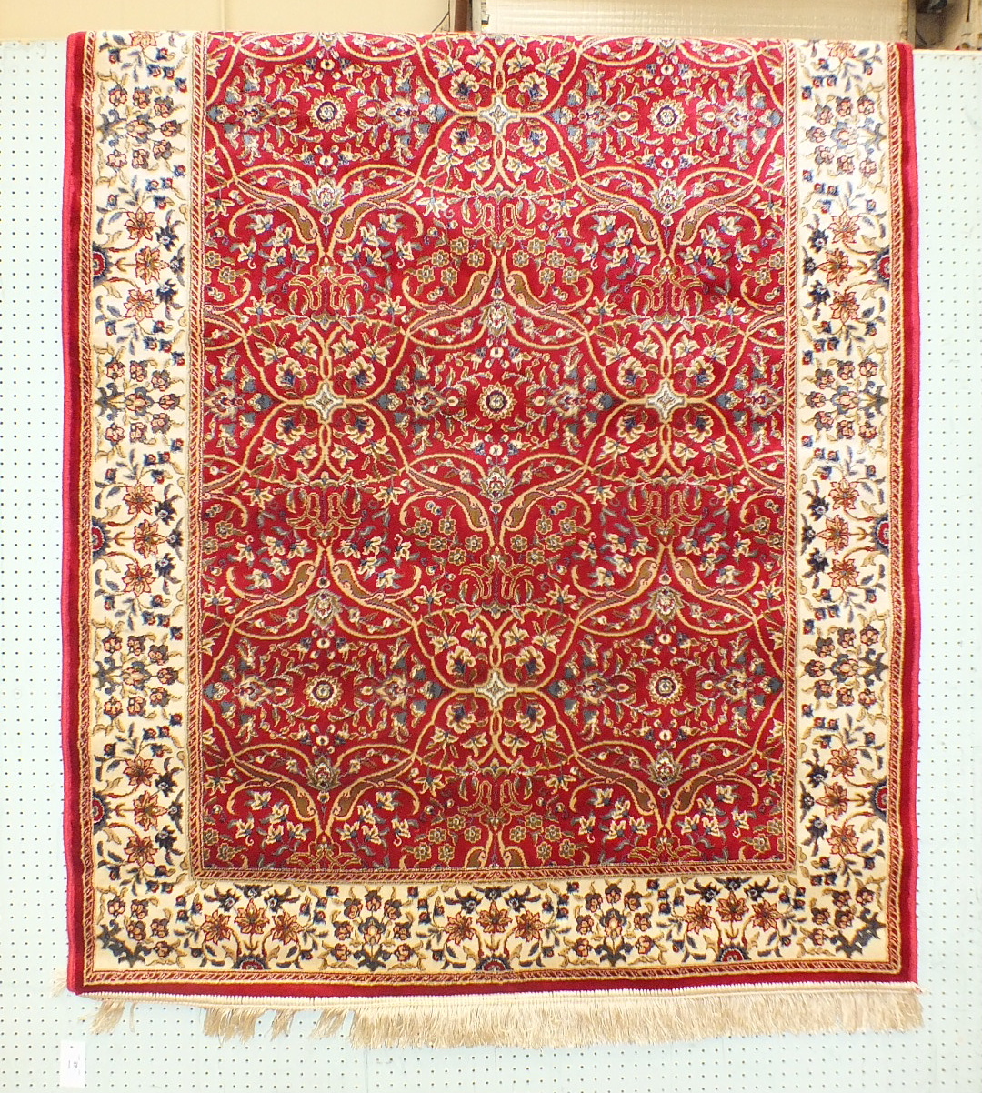 A similar rug with all-over foliate design, on red ground with ivory border.