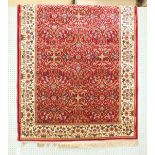 A similar rug with all-over foliate design, on red ground with ivory border.