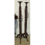 A pair of mahogany carved and turned bed posts converted as torchère stands, raised on tripod