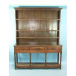 An antique oak dresser, the shelved plate rack with rows of iron cup hooks above three frieze