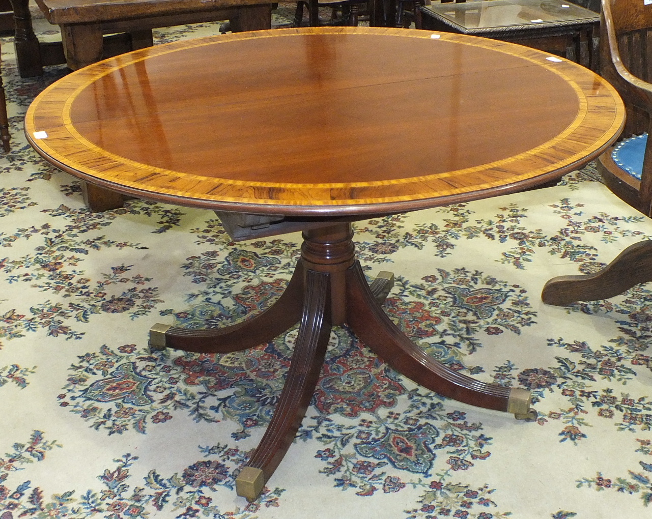 A reproduction mahogany circular dining table with inlaid and cross-banded decoration, on single