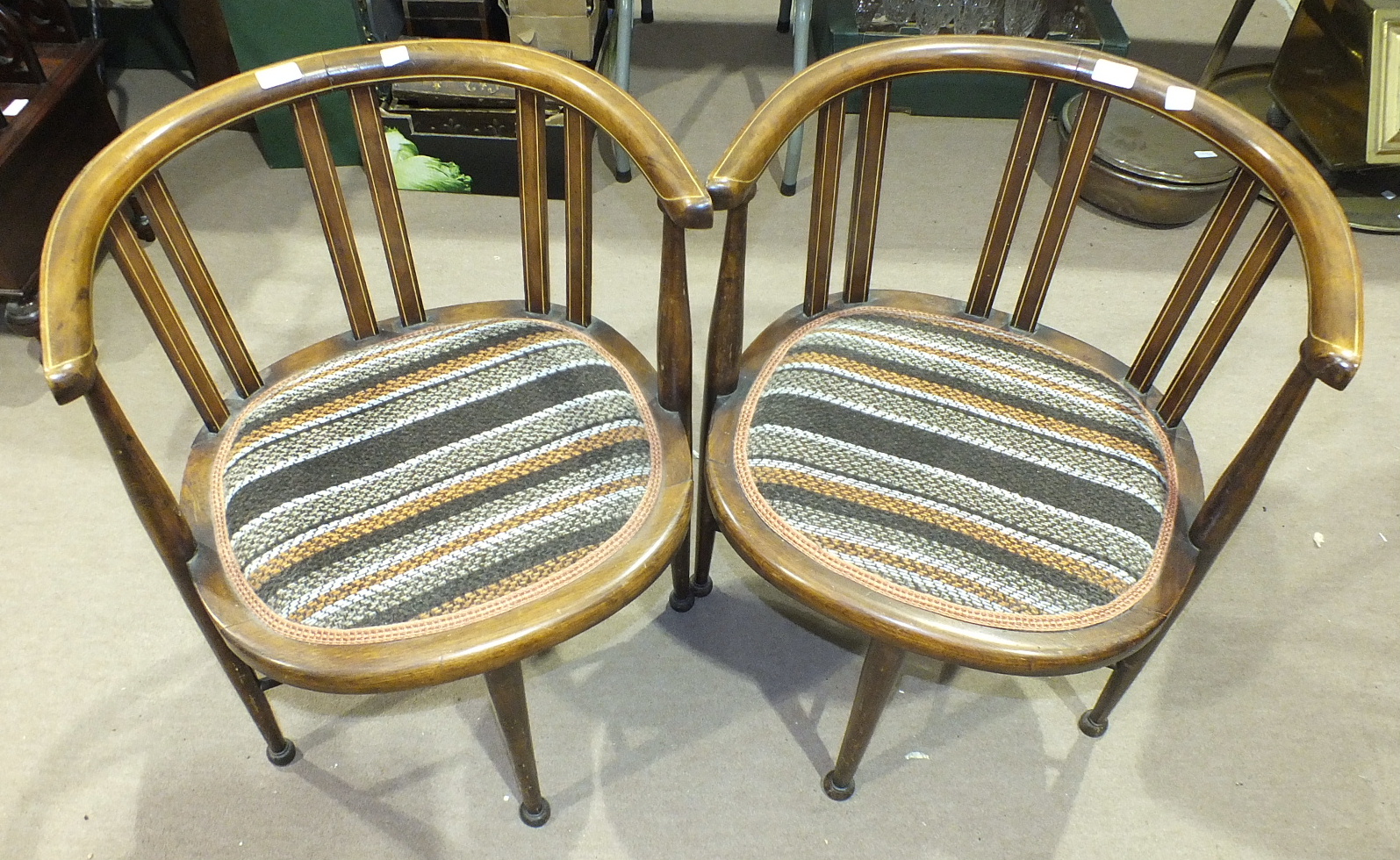 A pair of stained inlaid mahogany armchairs, each with padded seat on turned legs, a carved square-