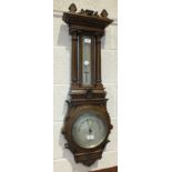 An Edwardian carved oak-cased barometer and thermometer, the 20cm diameter dial with Arabic numerals