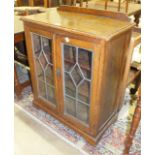 An oak low bookcase fitted with a pair of leaded-light doors, 70cm wide, 92cm high, an oak tea