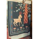 A modern knotted wool rug decorated with stylised animals and central tree on a green ground, 175