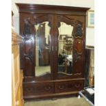 An Edwardian mahogany carved wardrobe, the cornice above a pair of mirrored doors, on two-drawer
