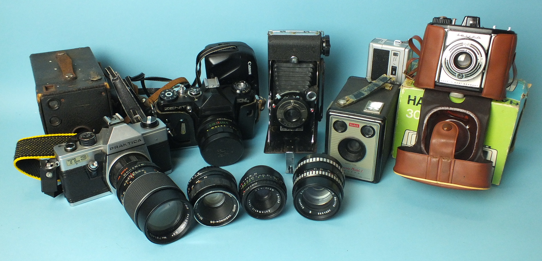 A collection of cameras and lenses, including Praktica TL3, Zenit EM and Kershaw Eight-20 Penguin.