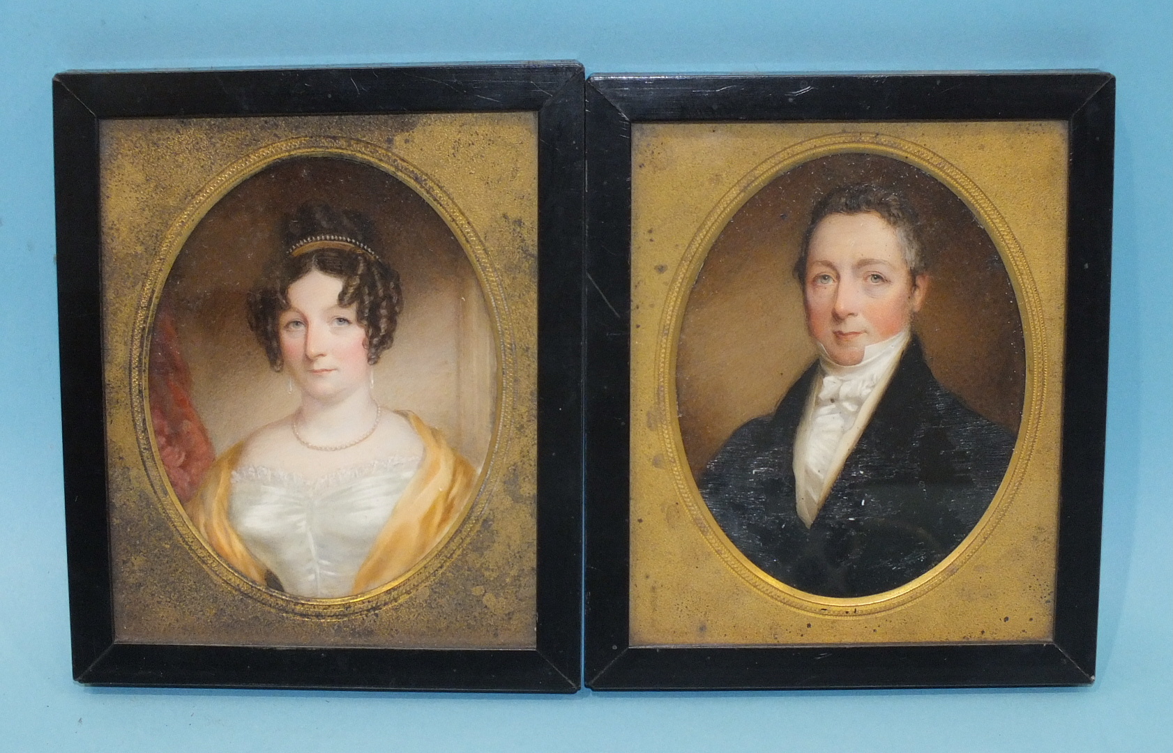 A pair of 19th century miniature portraits of a gentleman wearing a blue coat and white stock and