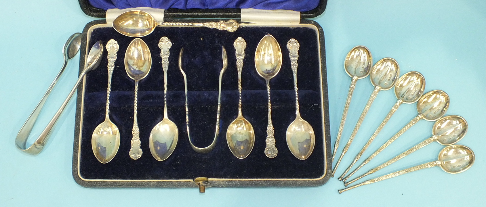 A cased set of six teaspoons and sugar tongs, (one extra spoon), another set of six teaspoons and