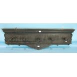 An antique carved oak hat or coat rack, the carved cornice and frieze having five turned hangers,