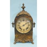 A simulated marble and gilt metal mantel clock of arch form with metal finial, carrying handle and