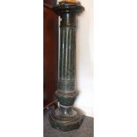 A large serpentine stone pedestal, the fluted and turned column supported on an octagonal plinth,